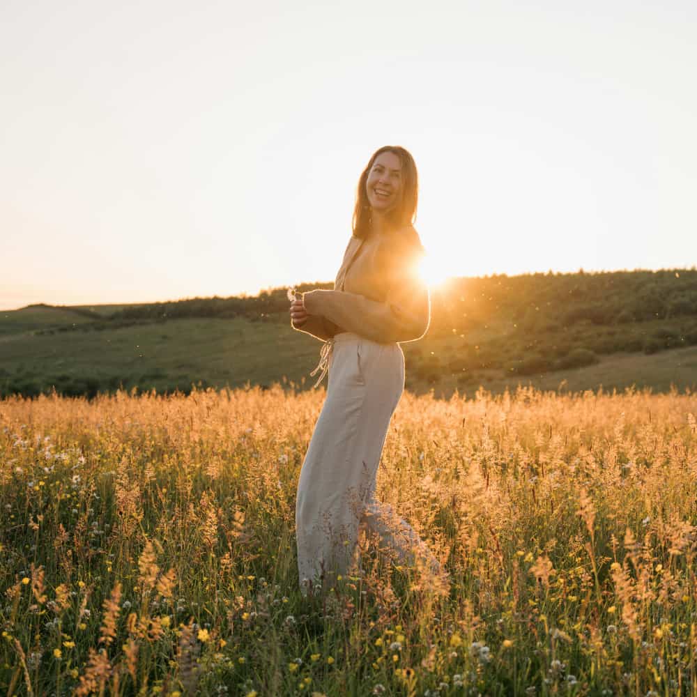 Woman stands on a hill at sunset with joy on her face from ketamine treatment in Benton County